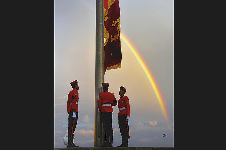 Soldater i Sri Lanka hissar en stor flagga och i bakgrunden syns en flagga