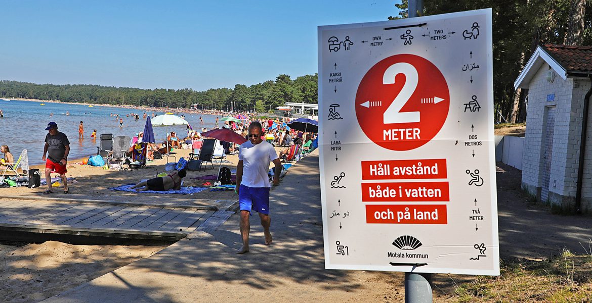 En strand i Motala i augusti 2020, skylt med coronariktlinjer