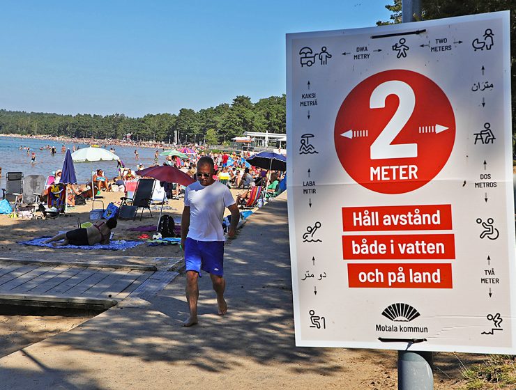 En strand i Motala i augusti 2020, skylt med coronariktlinjer
