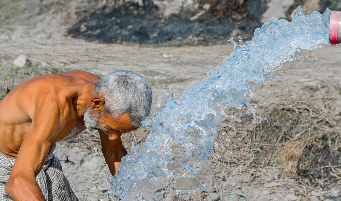 En man på landsbygden i Pakistan söker välbehövlig svalka under värmeböljan.
